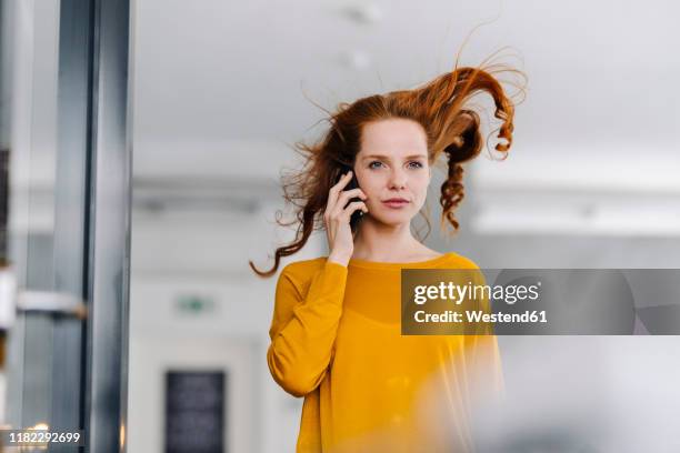 woman with windswept hair on the phone in office - tousled hair stock pictures, royalty-free photos & images