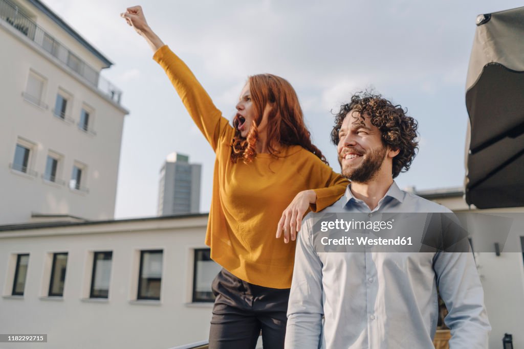 Woman with colleague on roof terrace clenching fist