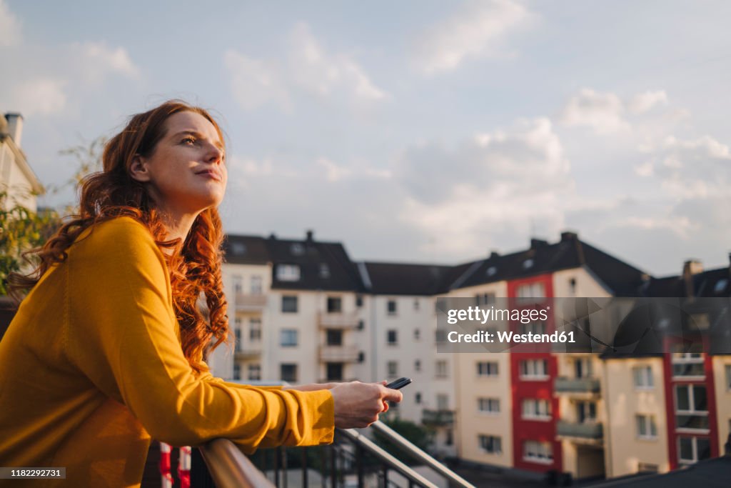 Redheaded woman standing on roof terrace