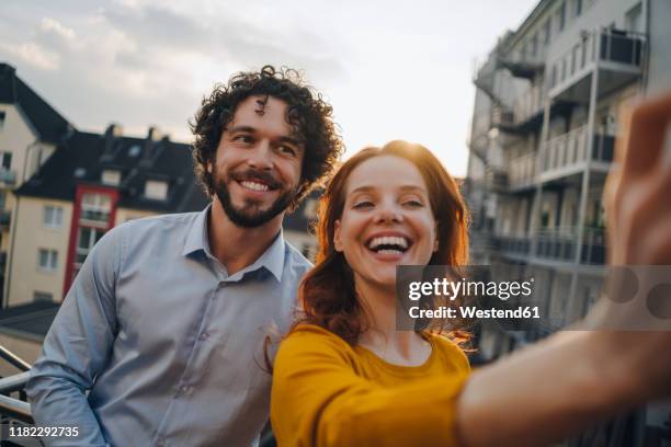 two happy colleagues on roof terrace taking a selfie - capelli rossi foto e immagini stock