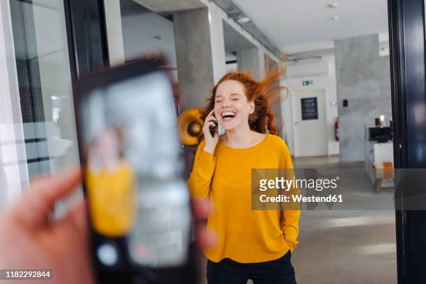 happy woman with windswept hair on the phone in office - hair flying stock-fotos und bilder