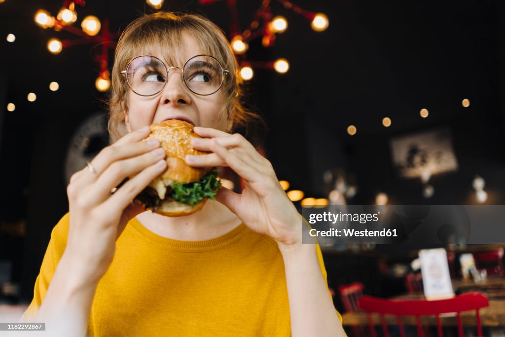 Young woman eating burger in a restaurant