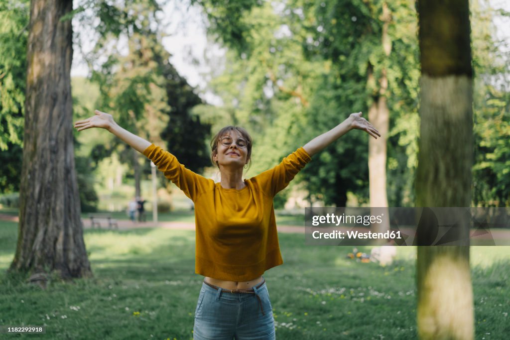 Young woman in a park with outstretched arms