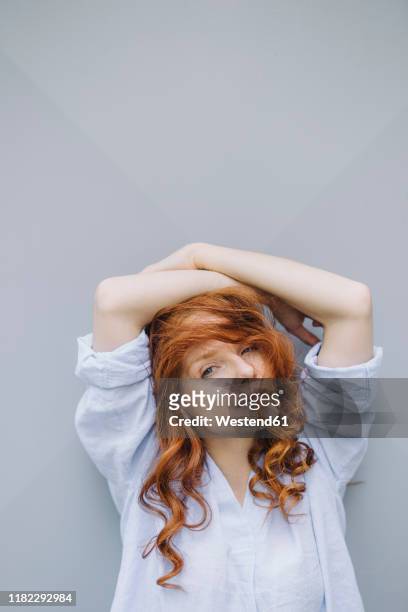 portrait of beautiful redheaded woman at a wall - grey blouse stock pictures, royalty-free photos & images