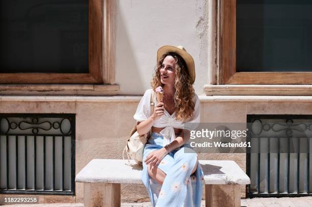 young woman sitting on stone bench eating ice cream - hot spanish women stock pictures, royalty-free photos & images