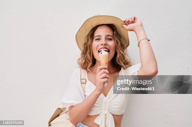 portrait of happy young woman with hat eating ice cream - blond women happy eating stockfoto's en -beelden