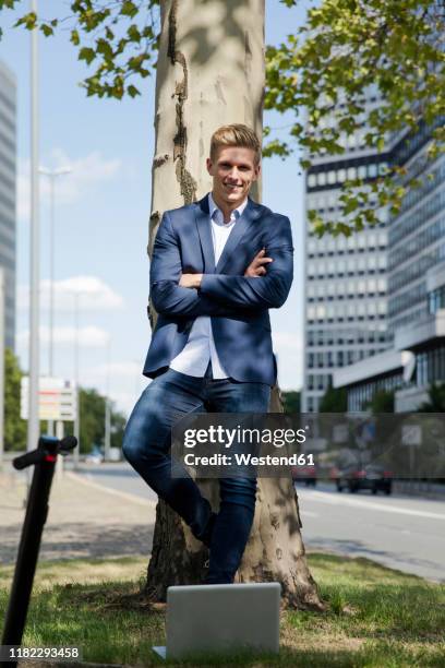 confident young businessman with e-scooter and laptop in the city - grass verge stock pictures, royalty-free photos & images