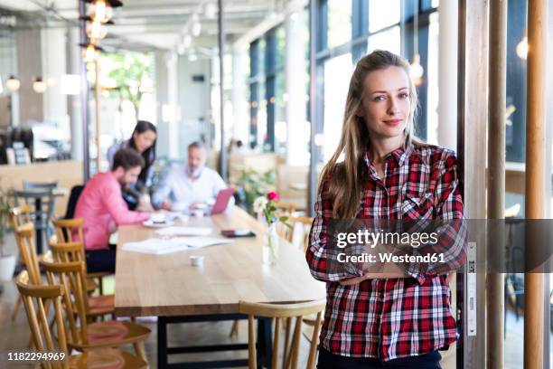 portrait of casual businesswoman in a cafe with colleagues having a meeting in background - founder bildbanksfoton och bilder