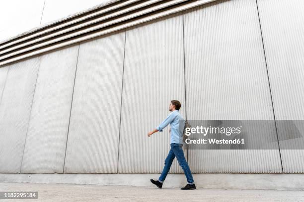 casual businessman walking along a wall - businessmen casual not phone walking stock pictures, royalty-free photos & images