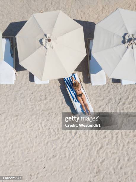 woman lying on sun lounger at the beach, gili air, gili islands, indonesia - umbrellas from above photos et images de collection