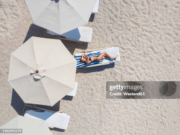 woman lying on sun lounger at the beach, gili air, gili islands, indonesia - umbrellas from above photos et images de collection