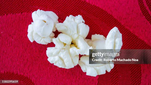 popcorn over a red surface - corn kernel stock-fotos und bilder