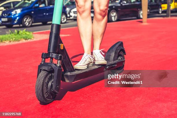 legs of young woman riding e-scooter on boulevard of the stars, berlin, germany - boulevard der stars berlin stockfoto's en -beelden