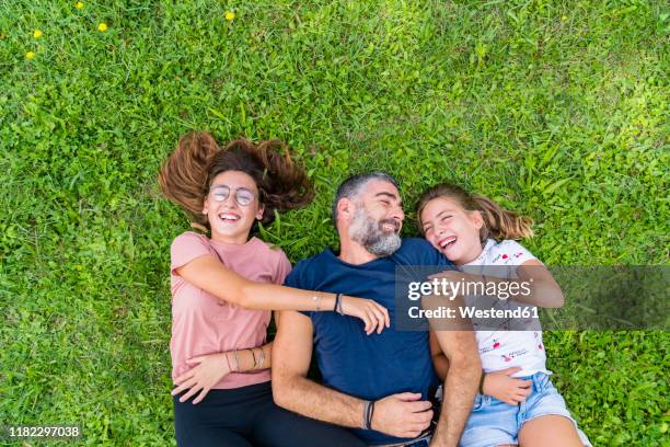 happy father with two daughters lying on a meadow - happy tween girls lying on grass stock pictures, royalty-free photos & images