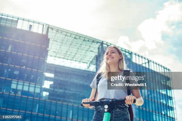 portrait of happy young woman with e-scooter in the city, berlin, germany - sustainable transportation stock pictures, royalty-free photos & images