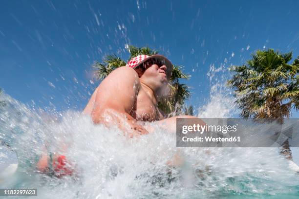 overweight man jumping into swimming pool - kanon stockfoto's en -beelden