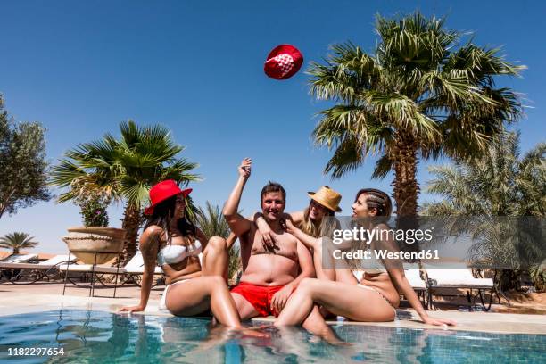 overweight man surrounded by affectionate beautiful women at the poolside - ugly woman stockfoto's en -beelden