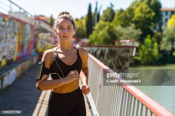 portrait of young woman running on a bridge - man running city stock-fotos und bilder