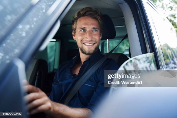 smiling young man in car - voiture conducteur photos et images de collection