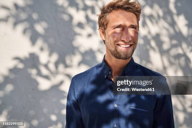 young man outdoors with shadow of leaves at the wall - plant shadow stock pictures, royalty-free photos & images