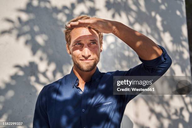 young man outdoors with shadow of leaves at the wall - schlagschatten stock-fotos und bilder