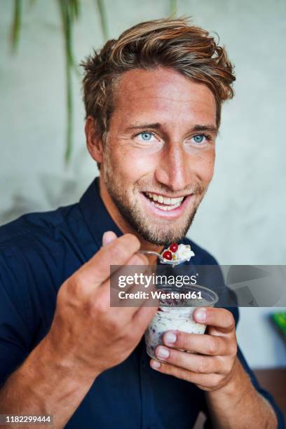 portrait of smiling young man eating muesli - one man only imagens e fotografias de stock
