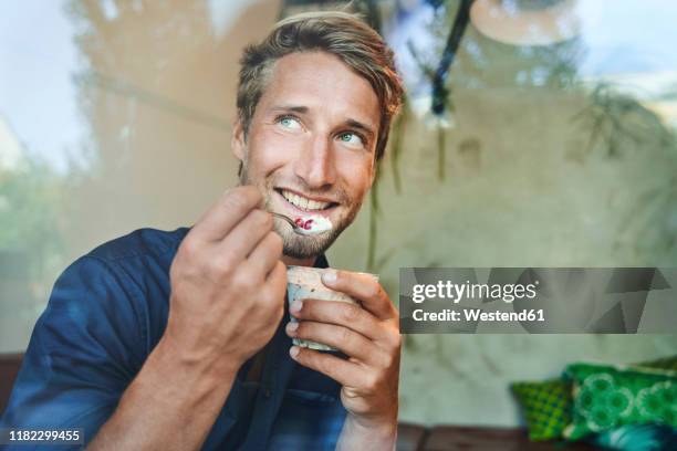 portrait of smiling young man eating muesli - man eating - fotografias e filmes do acervo