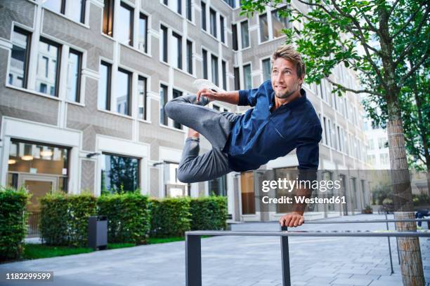 young man jumping over railing in the city - springen stock-fotos und bilder