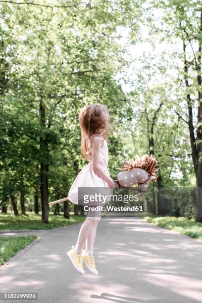 cute little girl in a park jumping with her hobbyhorse - hobby horse stock pictures, royalty-free photos & images