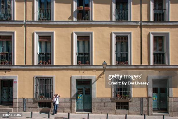 senior man taking a photograph in madrid old town - façade immeuble photos et images de collection