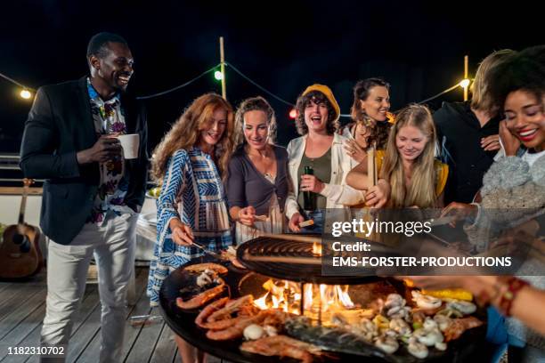 trendy group of people standing around the barbecue grill - bbq grill stock-fotos und bilder