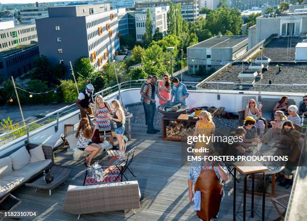 20 stylish, trendy co-workers enjoying office party grill on roof deck on sunny summer day - rooftop bbq stock pictures, royalty-free photos & images