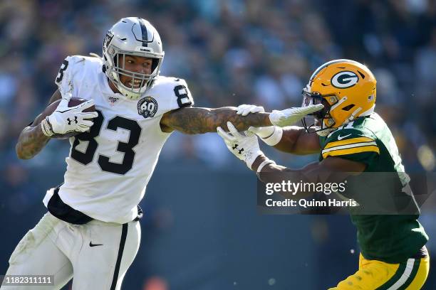 Darren Waller of the Oakland Raiders stiff arms Adrian Amos of the Green Bay Packers in the second half at Lambeau Field on October 20, 2019 in Green...