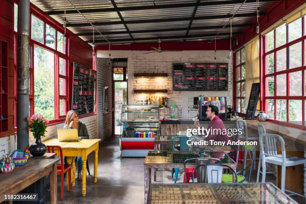 young man and woman with laptops talking in coffee shop - inside coffe store stock-fotos und bilder