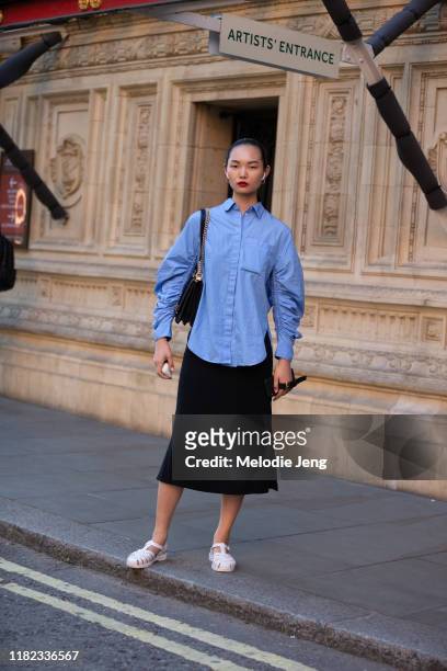 Model Ling Chen wears Airpods, a blue blouse, black skirt, and light pink jelly sandals after the Emilia Wickstead show during London Fashion Week...