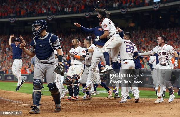 Gary Sanchez of the New York Yankees walks off the field as the Houston Astros celebrate a walkoff home run by Jose Altuve of the Houston Astros in...