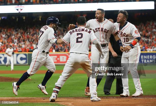 Jose Altuve of the Houston Astros is mobbed by Alex Bregman, Carlos Correa and Yuli Gurriel as he approaches home plate after hitting a walk-off home...