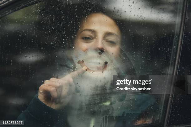 glückliche frau zeichnung smiley gesicht auf autofenster während regentagen. - winter car window stock-fotos und bilder