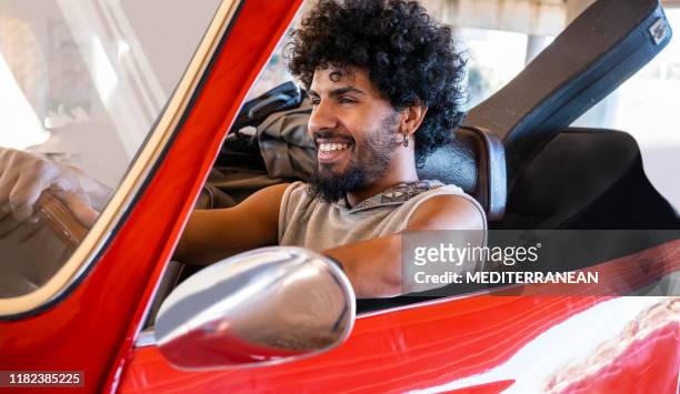 ethnic young guide man driving a red generic car convertible - man driving sports car stock pictures, royalty-free photos & images