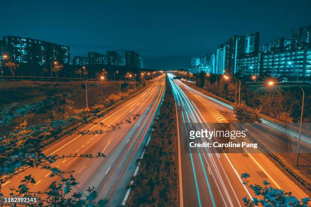 light trails along a busy highway. - singapore travel stock pictures, royalty-free photos & images