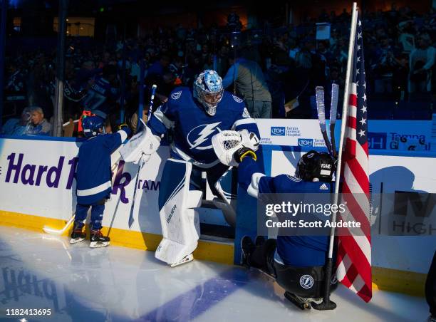 Goalie Andrei Vasilevskiy of the Tampa Bay Lightning steps on to the ice and bumps gloves with Thunder Kid skater, Aidan Smith, and Sgt. Sam Smith,...