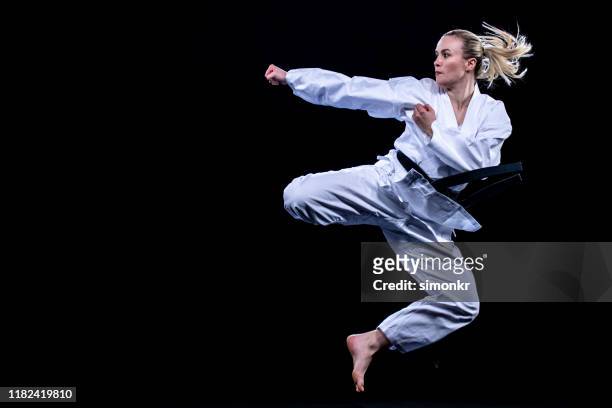 giocatrice di karate femminile che salta in aria per il calcio - karate foto e immagini stock
