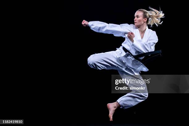 female karate player jumping in air for kick - black belt martial arts stock pictures, royalty-free photos & images