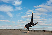 Street dancer hipster guy makes back flip with arm support on the roof outdoor.