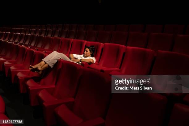 woman lying down alone in a movie theater - movie still stock-fotos und bilder