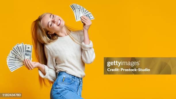 Blissful millennial girl holding lots of money and enjoying success