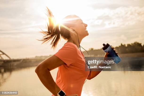jeune femme courant contre le soleil de matin - joggeuse parc photos et images de collection