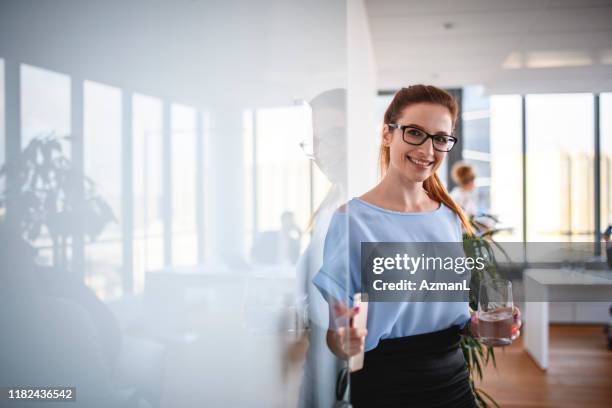 glimlachend kaukasische zakenvrouw opening kantoor voordeur - introductory stockfoto's en -beelden