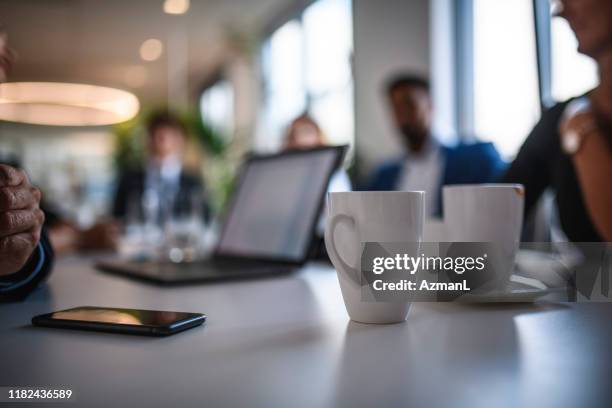 koffie mokken en smart phone op vergadertafel - conferentietafel stockfoto's en -beelden