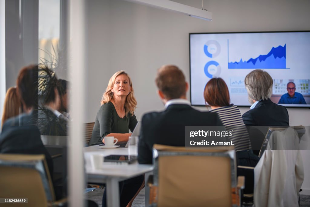 Mujer empresaria que escucha a la asociada durante la videoconferencia